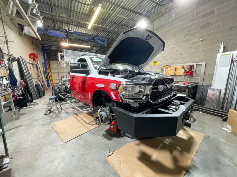 Exterior view of small fire truck showing cab, body compartments, and wheel/tire area.